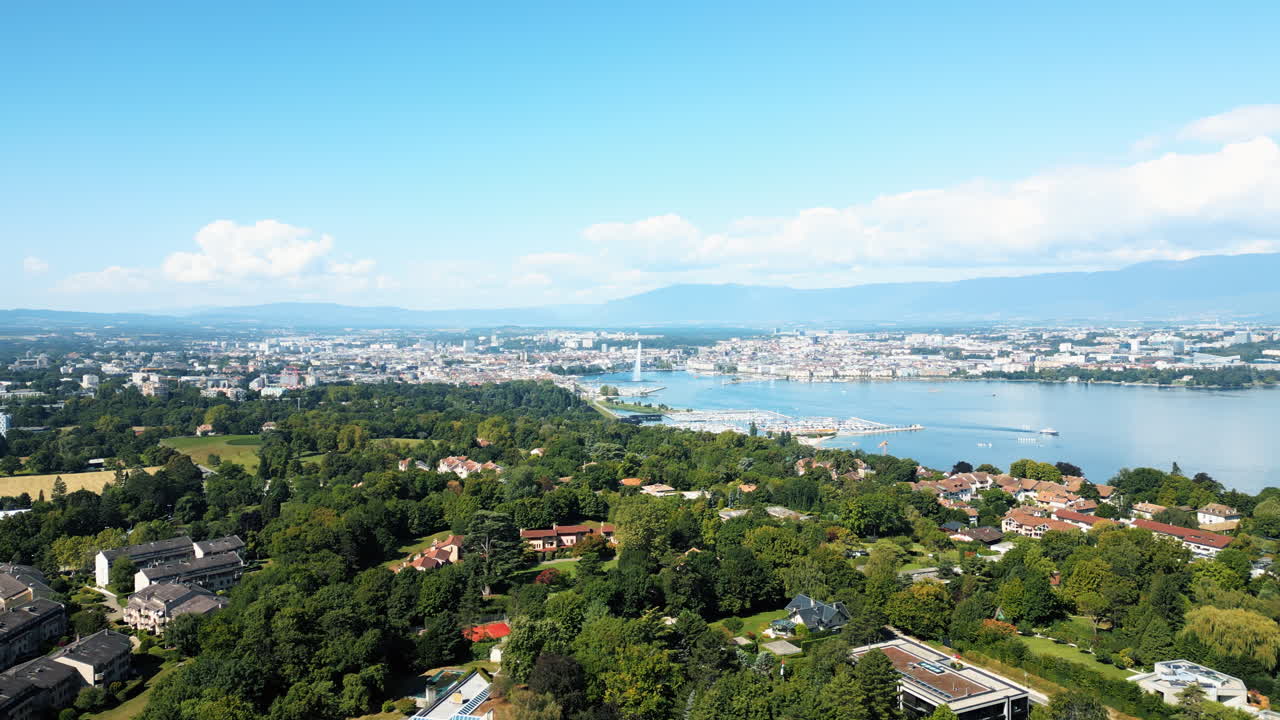Pan drone shot of water fountain of Geneva during the day (Rade of Geneva) from Cologny, Switzerland