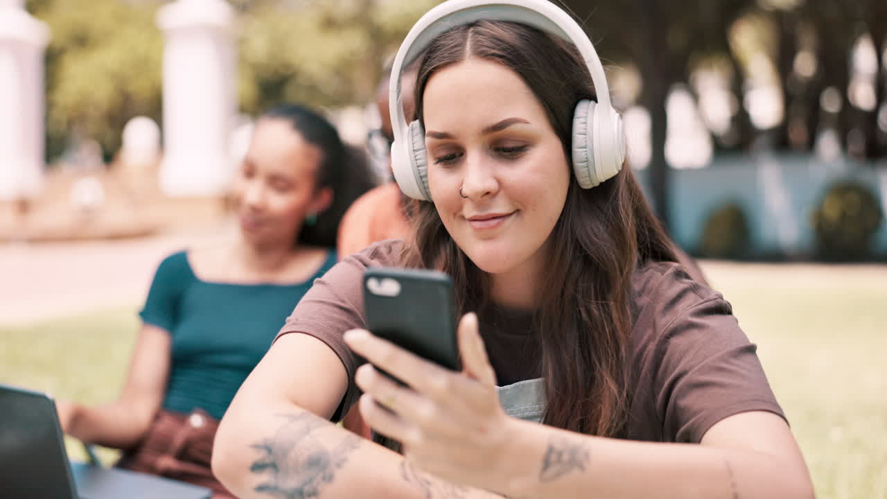 공원에서 스마트폰을 사용하는 헤드폰을 가진 젊은 여성
