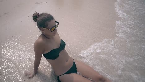 lady in bikini lies on clean sand beach and enjoys waves