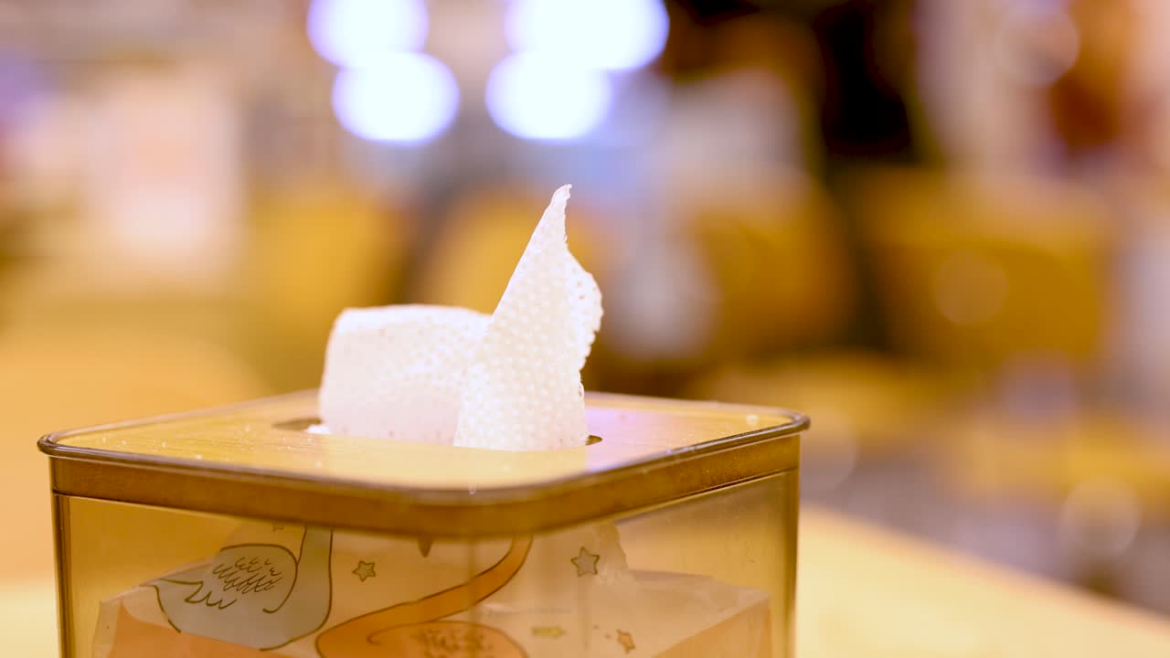 Stationary tissue box on tabletop, warm indoor lighting, shallow depth of field, soft background blur