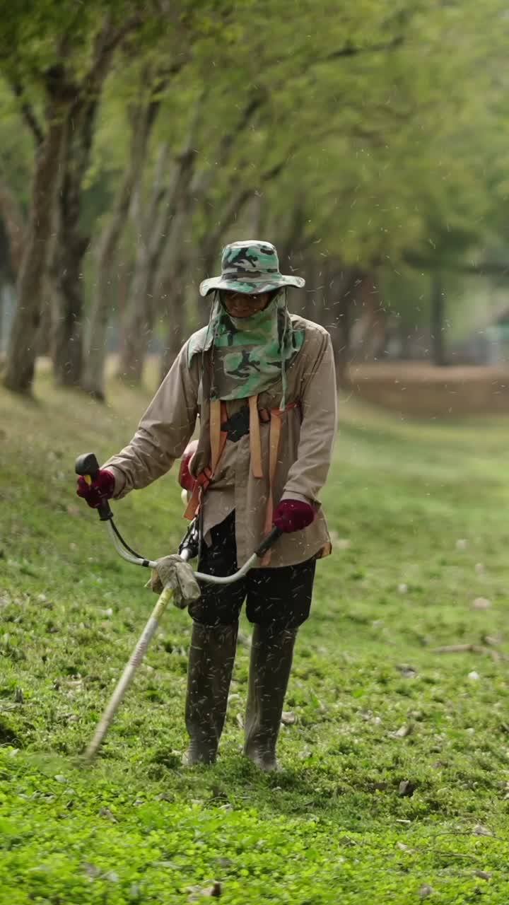 A gardener cutting grass with a brushcutter