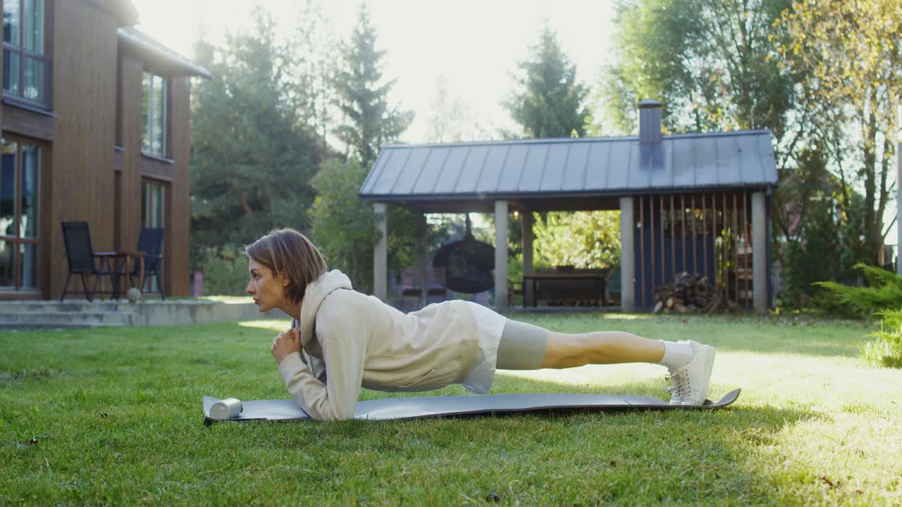 mujer haciendo ejercicio de tabla en un jardín