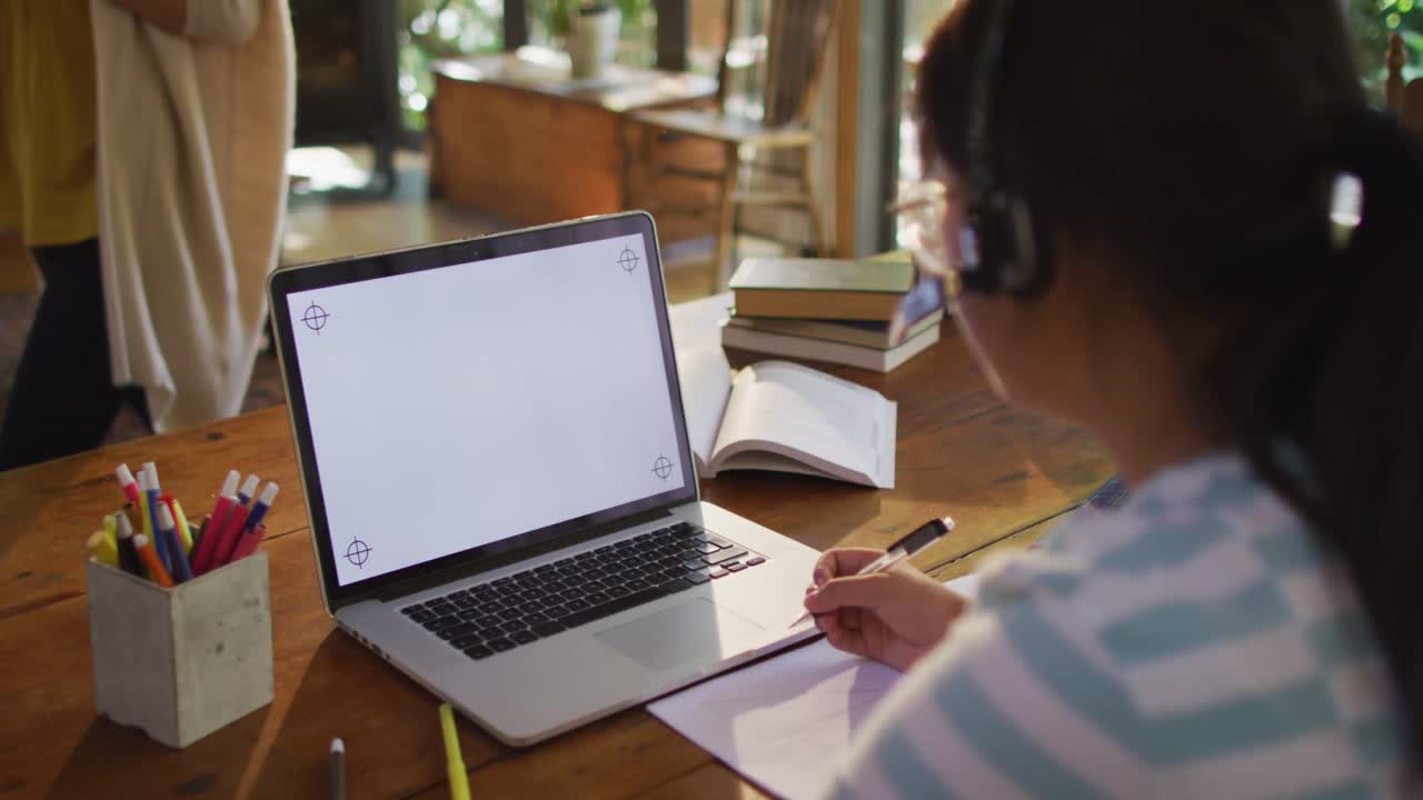 Asian woman sitting at table and using laptop with copy space, making video call