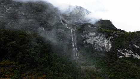 misty clouds float majestically in front of tendril waterfalls in new zealand