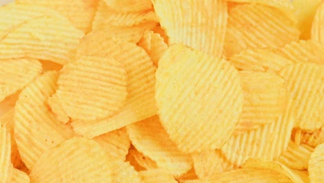 looped spinning yellow wavy potato chips full frame close-up background