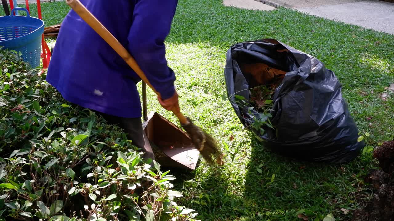 persona barriendo hojas, recogiendo desechos de jardín