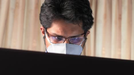 persona que trabaja en una computadora portátil con una máscara y gafas