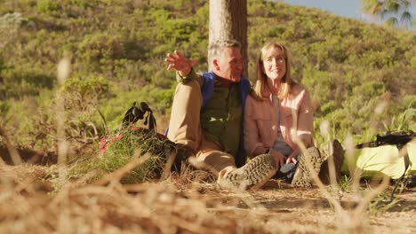 pareja de ancianos activos sentados en el suelo en el bosque