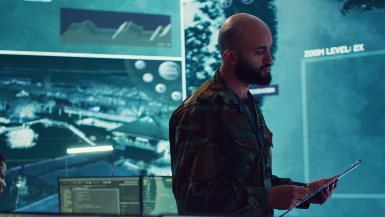 Army officer examining real time satellite data on big screen in military base