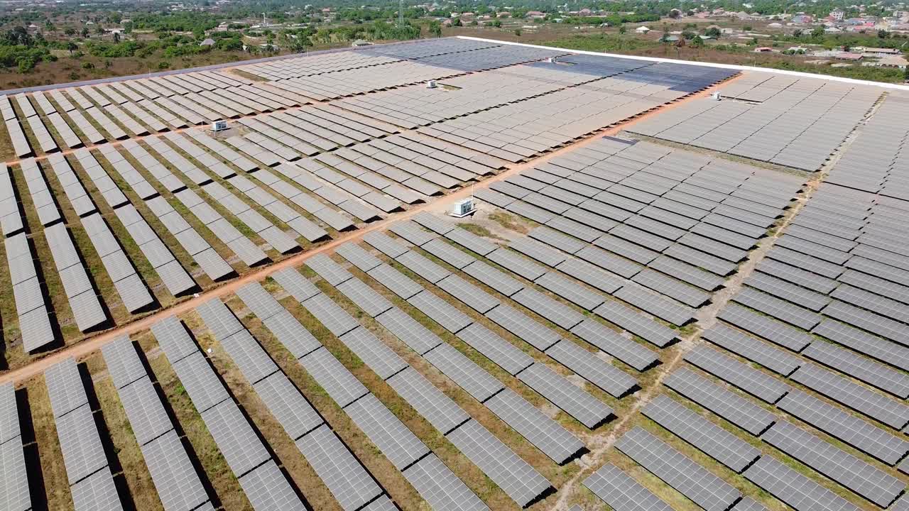 Aerial high tilt down overview of medium voltage power utility inverters and very dirty solar panels