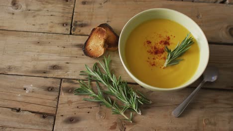 video of cream vegetable soup in bowl on wooden table with rosemary