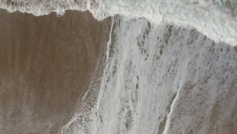 Afternoon-camera-down-drone-view-from-the-water-and-foamy-waves-of-Redondo-Beach,-California