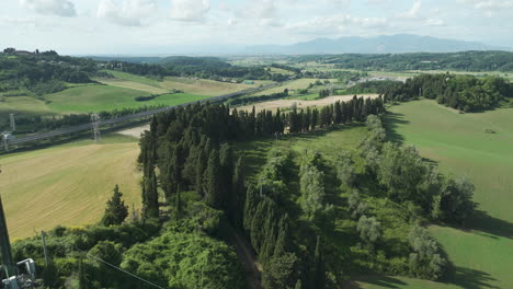 italian countryside with lush fields, forest, and distant mountains, aerial view