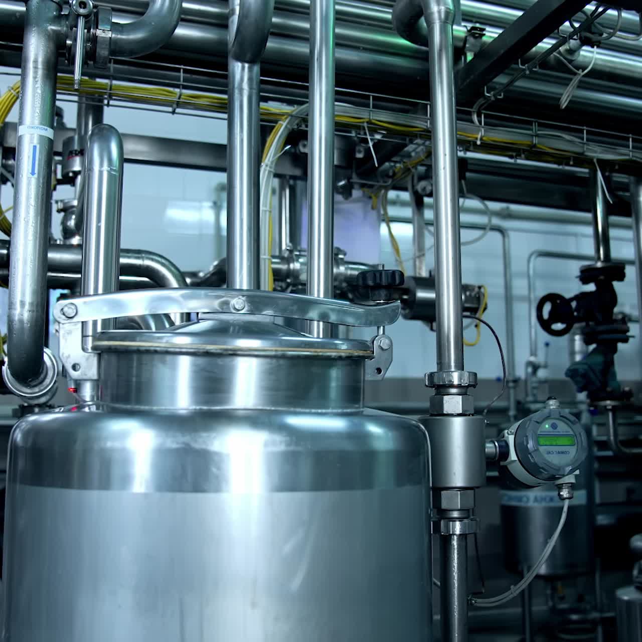 Large cistern closed tightly placed among the numerous metal pipes at dairy plant. Special equipment for storing and fermenting milk