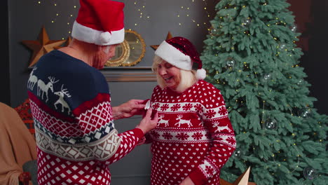 Liebevoller-Großvater-Schenkt-überraschter-Großmutter-Weihnachtsgeschenk-Schmuckschatulle-Mit-Goldenem-Ring