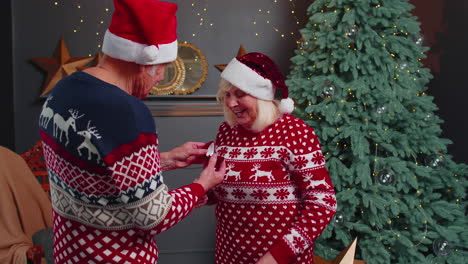 amoroso abuelo regalando regalo de navidad caja de joyas con anillo de oro a la abuela sorprendida