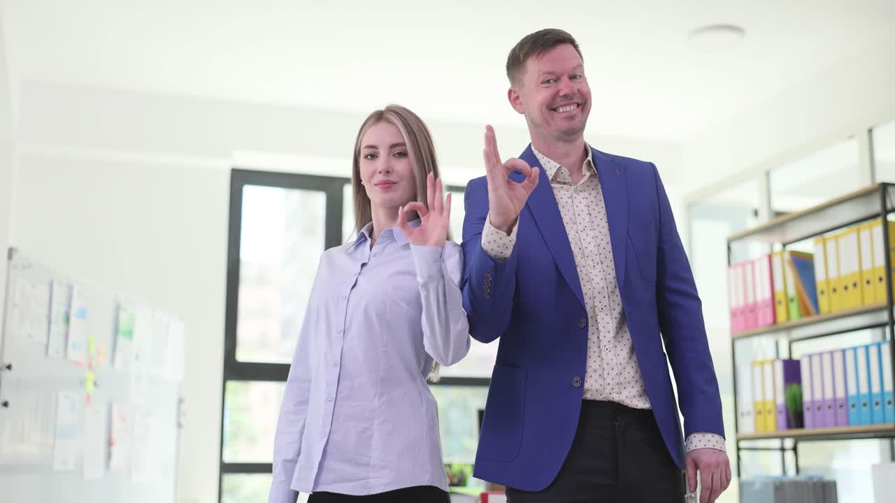 Two business people give the okay sign in the office