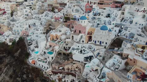 vista de avión no tripulado en grecia volando sobre santorini con la ciudad de oia casas blancas y techos azules en un acantilado junto al mar mediterráneo al amanecer
