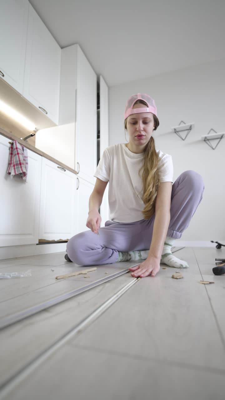 Vertical video shows a woman facing difficulty while fixing a floor transition strip, emphasizing learning, problem solving, and hands-on home repair in a real domestic setting
