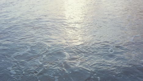 close-up of waves coming to the beach at sunset