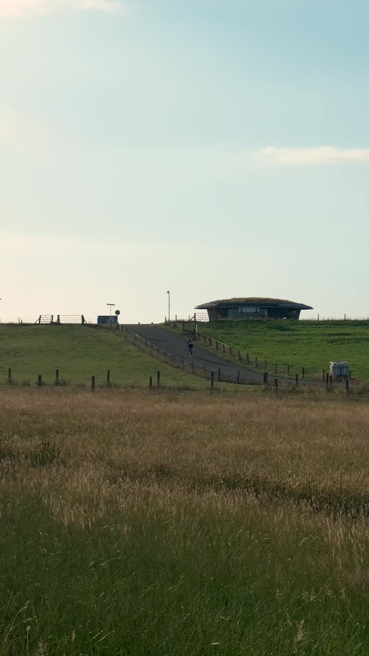 A rural landscape featuring a unique earth-sheltered house on a grassy hill