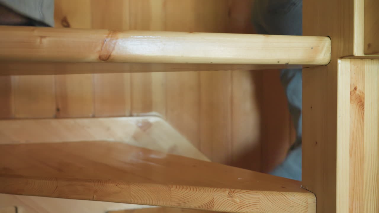 leg view of person in casual footwear climbing wooden staircase inside cozy rustic home, framed by smooth pine textures, capturing motion, indoor lifestyle, and warmth of natural timber environment