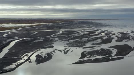 sobrevuelo aéreo del delta del río en islandia durante el día soleado y nublado - océano en el fondo