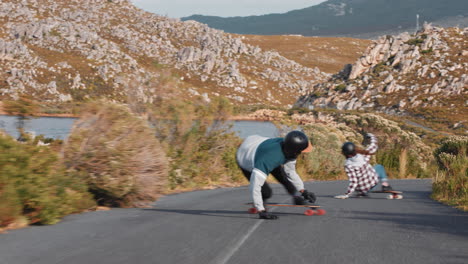 jóvenes amigos haciendo longboard juntos subiendo rápido cuesta abajo haciendo trucos adolescentes divirtiéndose haciendo skateboard en la carretera del campo disfrutando de unas vacaciones de verano relajadas vista trasera