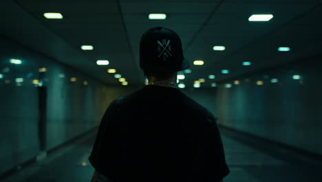 man walking in a dark subway tunnel at night