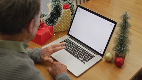 Caucasian-senior-man-sitting-at-table-making-video-call-at-home-on-laptop-with-copy-space-on-screen