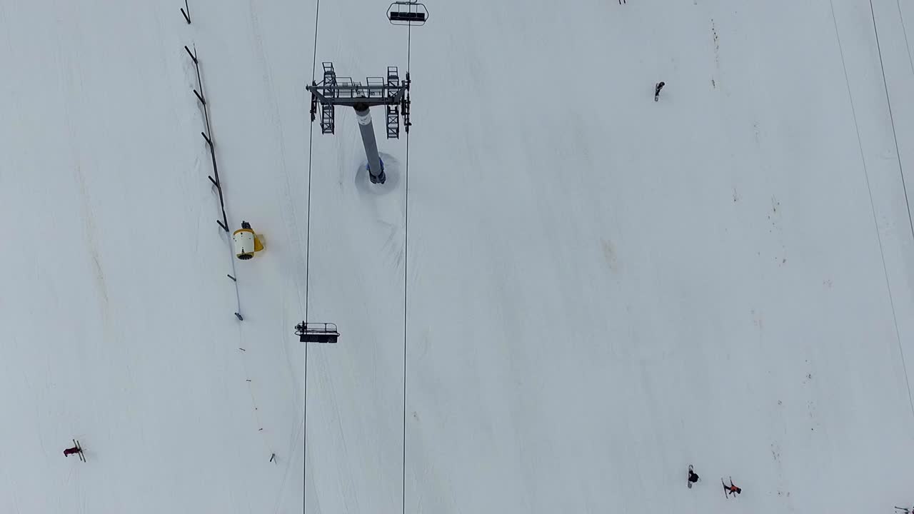 Empty chairlift zenith view and people skiing in Alto Campoo ski resort aerial shot