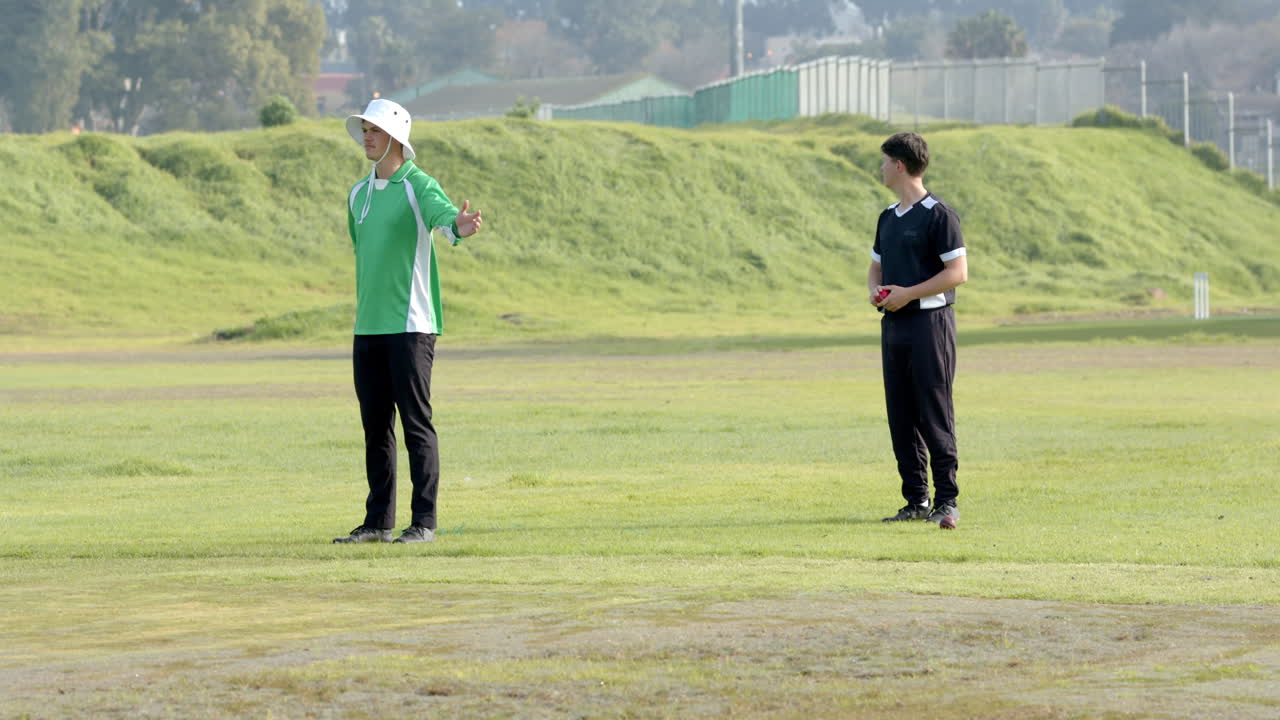 Playing cricket, bowler running towards wicket with umpire watching closely
