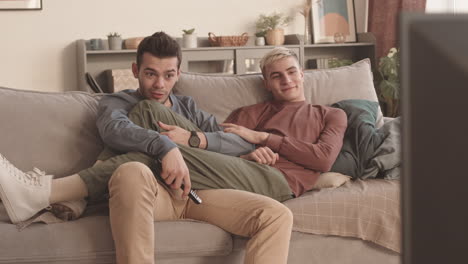 two young men resting and watching tv