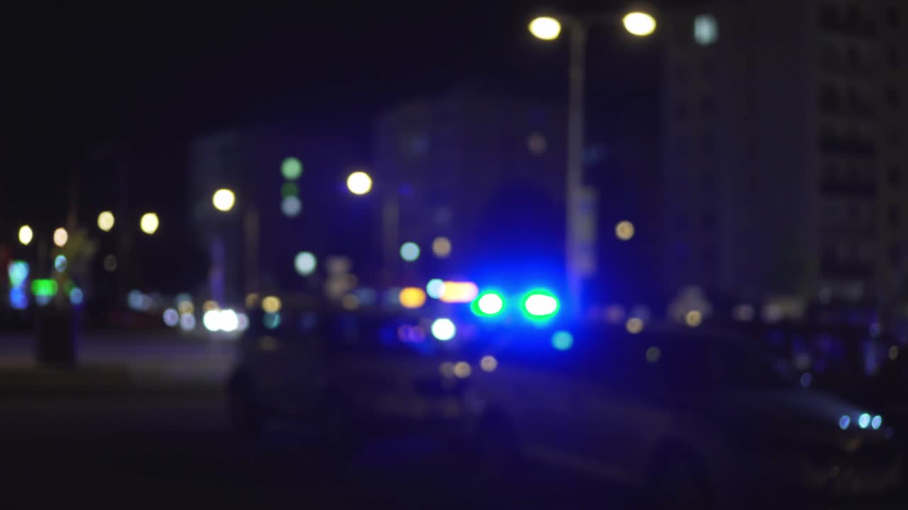 Police blue lights at night and parking lot with few cars, blurry view of traffic accident symbolism