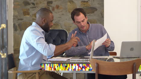 Two-men-working-together-at-computer-in-boardroom,-slow-motion