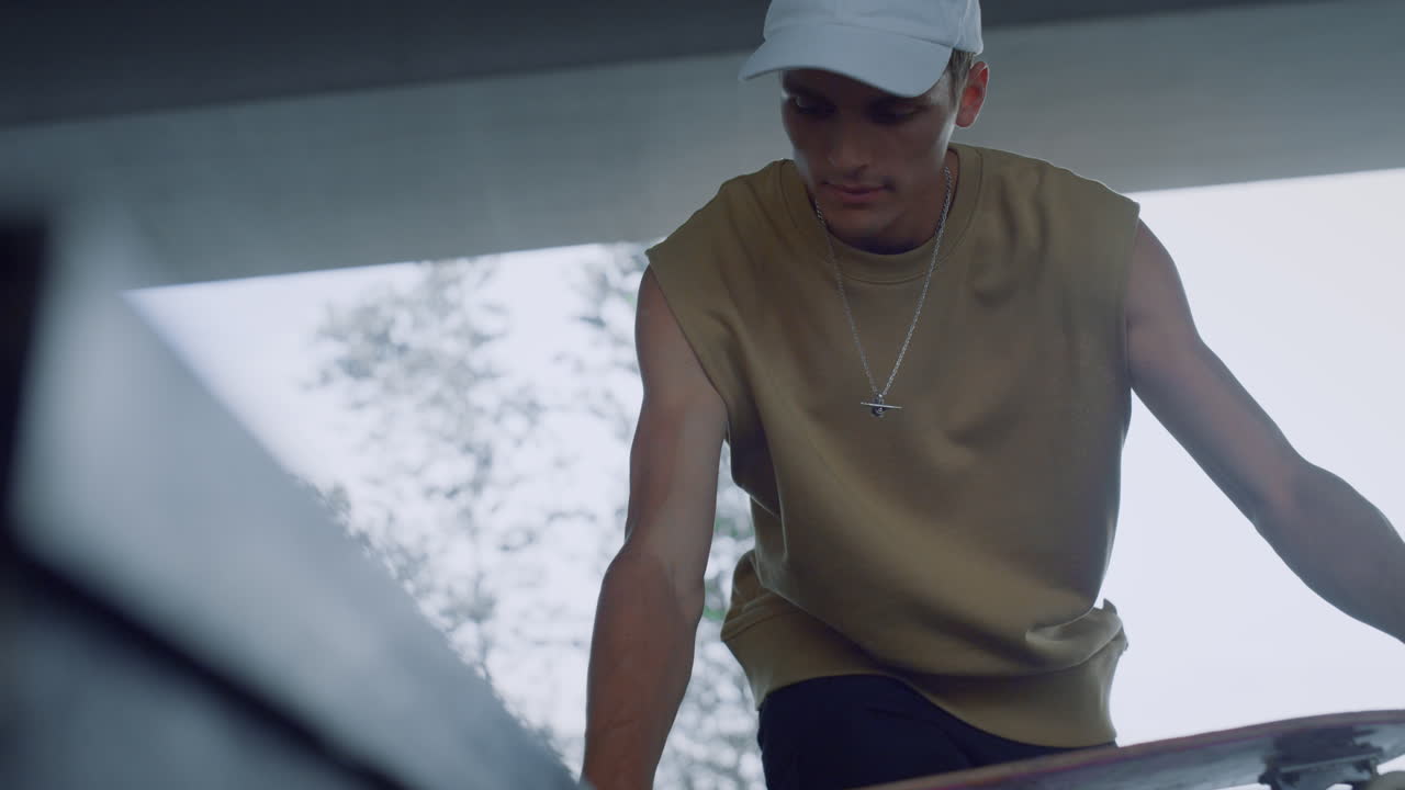 활발한 스케이트 선수가 야외에서 스케이트 보드 훈련을 준비하고 있습니다. 스케이트 보드를 회전하는 남자.