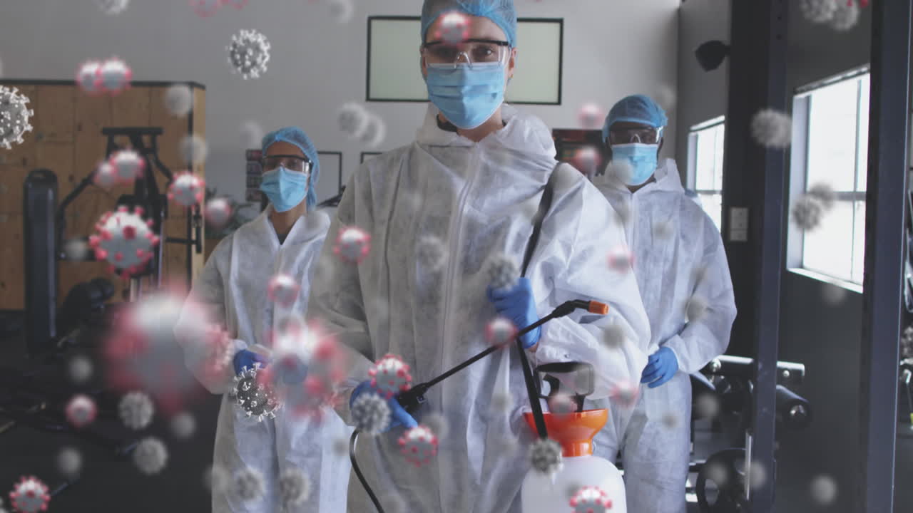 múltiples células de covid-19 sobre un grupo de trabajadores de la salud con un pulverizador de desinfectante en el gimnasio