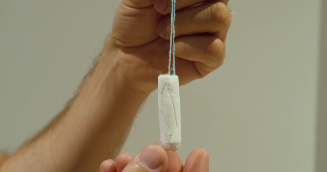 Close-up of an unused tampon held in hand. Ideal for menstruation, feminine hygiene, women's health, and medical education concepts.