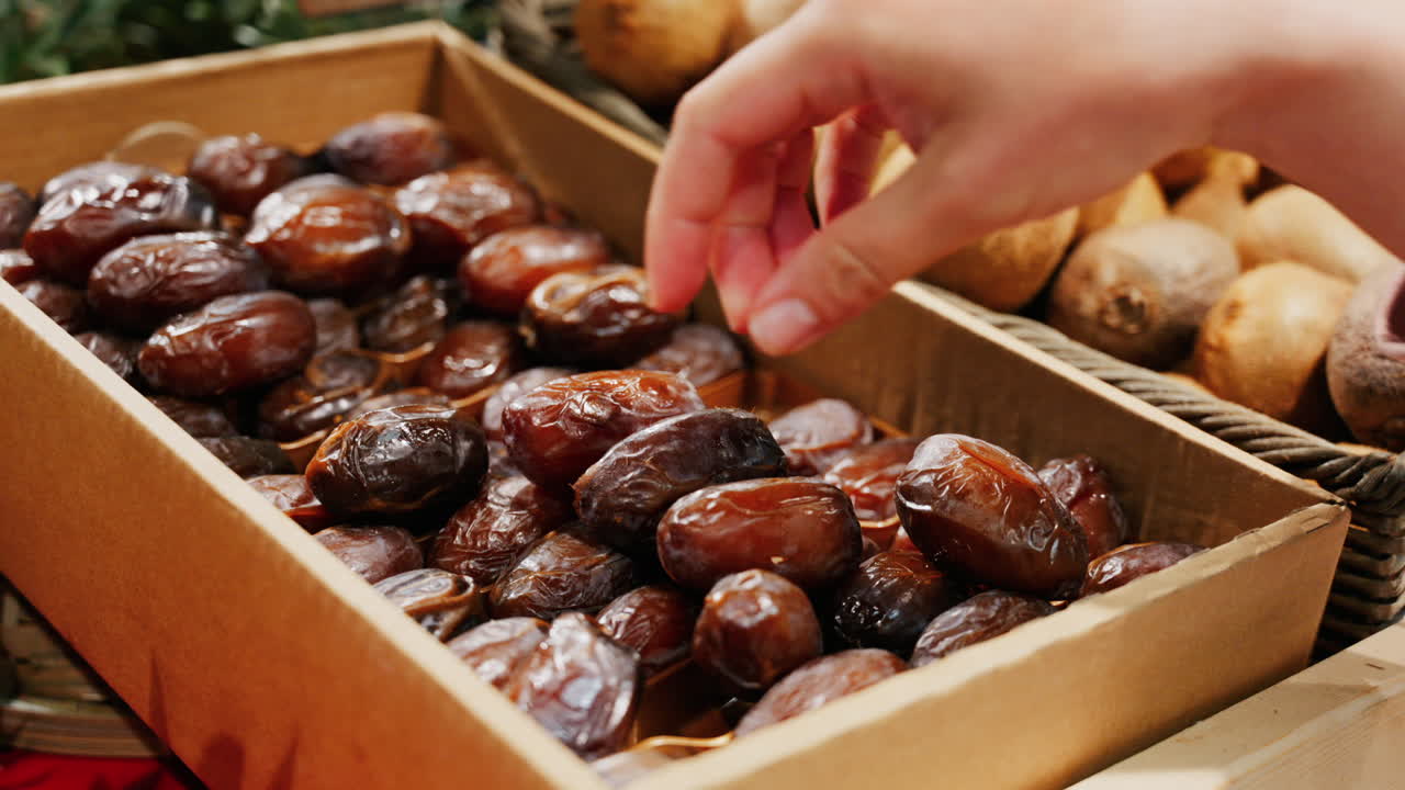 Close up of a woman's hand picking up dates at a market