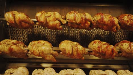 pollo en el asador giratorio con sabrosa piel asada de color amarillo dorado en cuatro filas - cámara lenta
