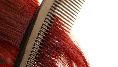 peine pasando por el pelo rojo rizado, primer plano