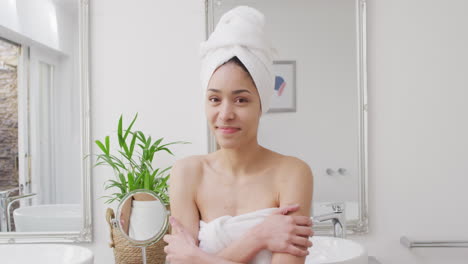 retrato de una mujer biracial con una toalla sonriendo en el baño