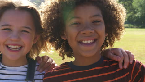 close up of pre-teen friends in a park smiling to camera