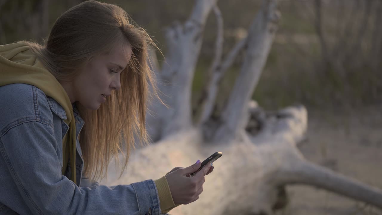 playa al atardecer y chica usando teléfono inteligente para chatear