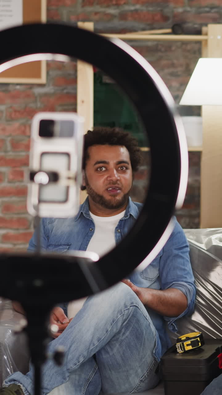 African-American host talks to builder with contemporary screwdriver recording video for blog in living room. Professional constructors give tips