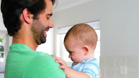 Padre-Feliz-Sonriendo-Y-Sosteniendo-A-Su-Bebé-