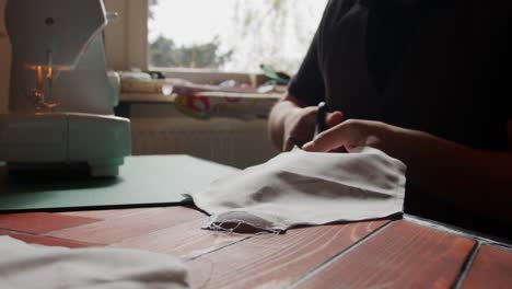 seated person cuts fabric along a seam with natural light behind. slow motion