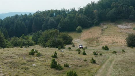 Vista-Aérea-De-La-Montaña-En-Otoño-Y-Vehículo-Todoterreno-En-La-Carretera-Polvorienta