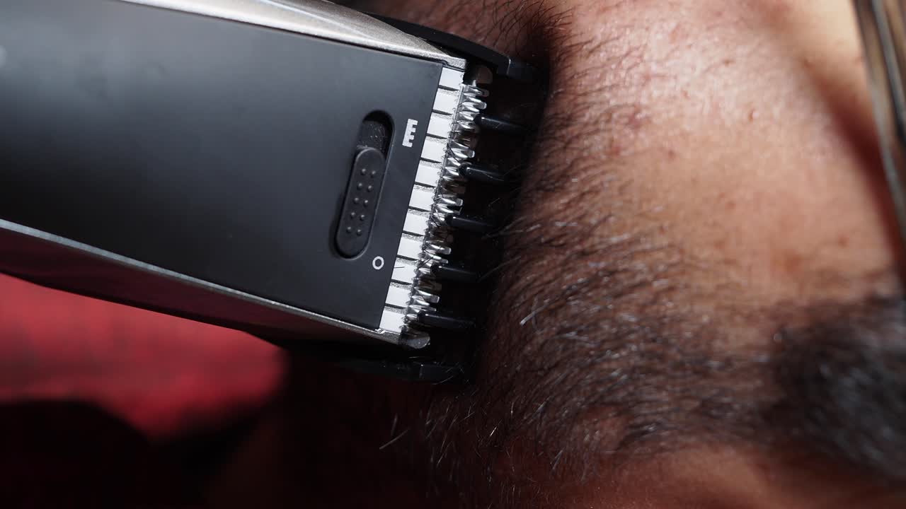 Man trimming his beard with an electric shaver