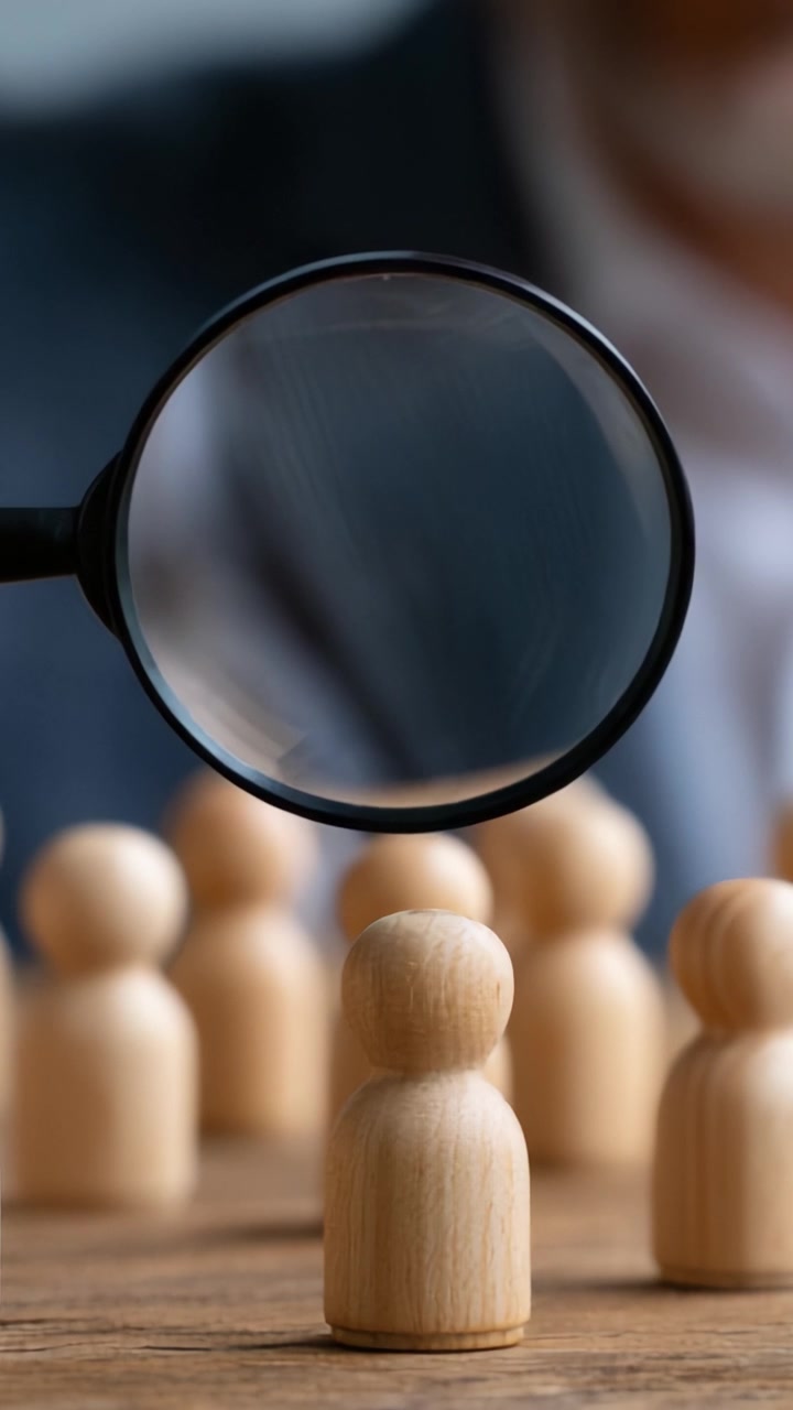 A Detailed Examination of Wooden Figurines Through a Magnifying Glass, Illustrating Focus and Attention to Detail in the Analysis of Simulated Human Interactions